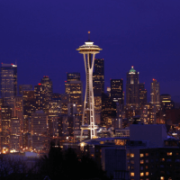Seattle skyline at dusk, featuring the iconic Space Needle illuminated against a backdrop of shining city lights.